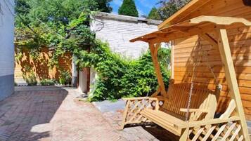 A wooden deck with a swing chair and a wooden pergola.