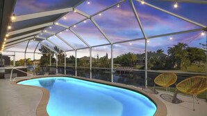 Une piscine entourée d’une paroi de verre, avec des chaises tout autour et une vue sur le ciel.