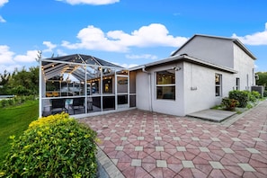 A modern building with a glass enclosure, a patio area, and a well-maintained garden.