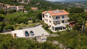 A two-story building with a red-tiled roof, a balcony, and a driveway with two cars parked. - Bela Vista 4 (Bregi)