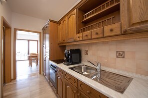 A kitchen with wooden cabinets, a stainless steel sink, and a coffee maker.