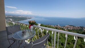 A balcony with a table and chairs, overlooking a coastal town and the sea. - Bela Vista 4 (Bregi)
