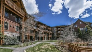 A multi-story lodge with a wooden exterior, a covered outdoor area, and a pathway leading to the entrance. - Keystone Ski area, Epic mountains views, Ground floor condo, short walk to lift  (Keystone)
