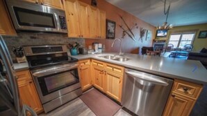 A modern kitchen with stainless steel appliances, wooden cabinets, and a large island with a sink. - Keystone Ski area, Epic mountains views, Ground floor condo, short walk to lift  (Keystone)