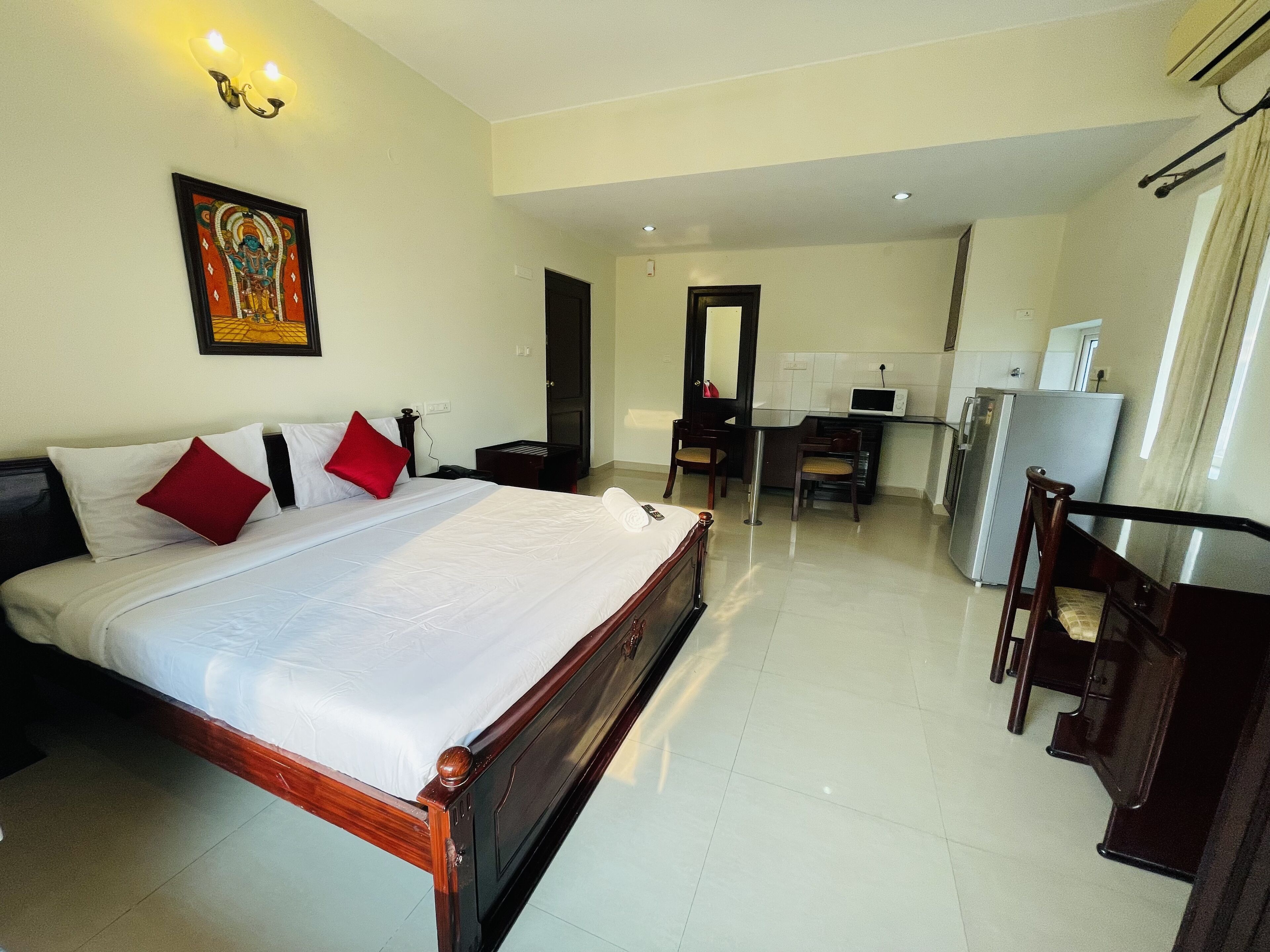 A hotel room with a large bed, a desk, and a refrigerator.