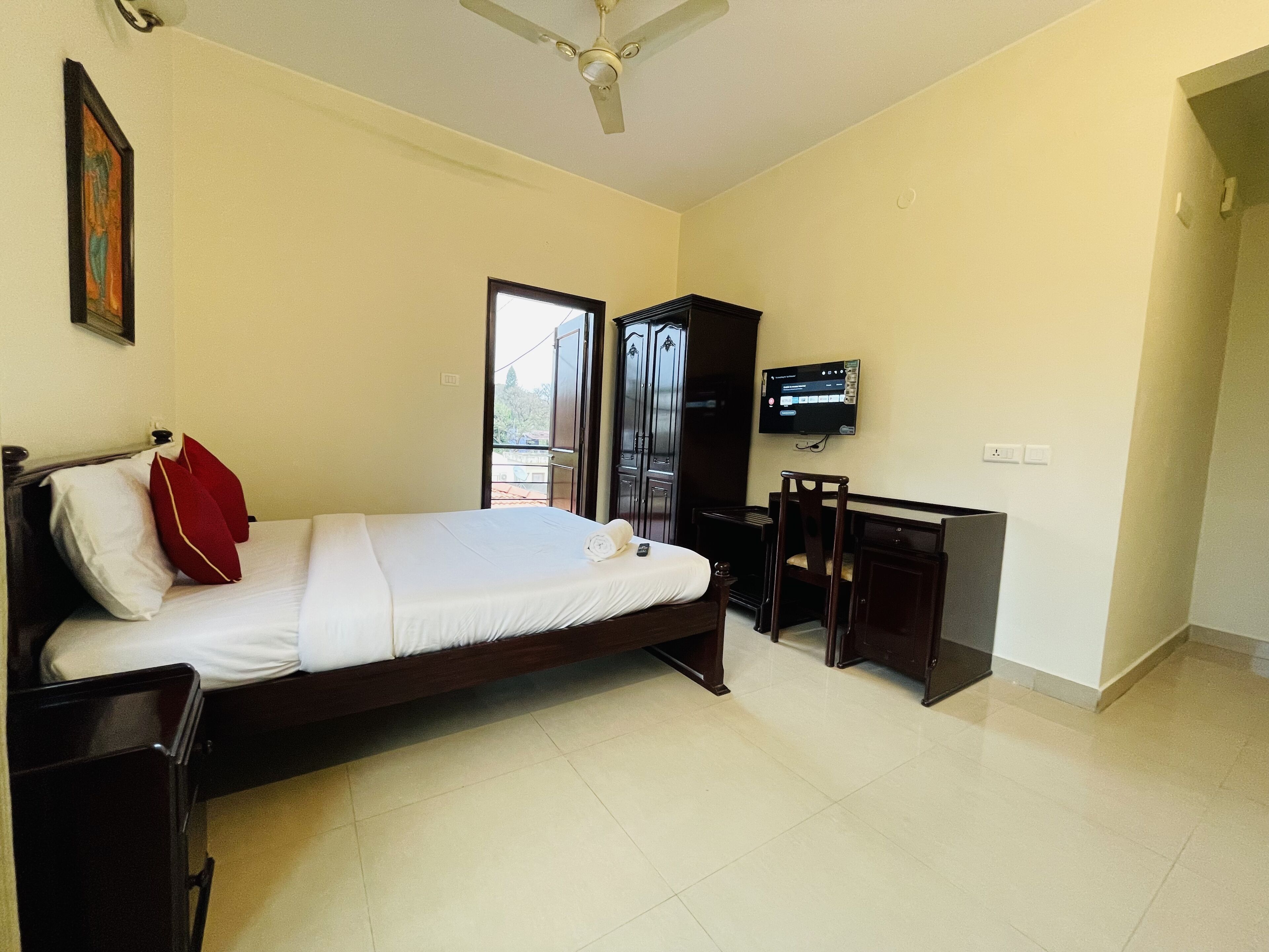 A hotel room with a bed, a desk, a chair, a television, and a ceiling fan.