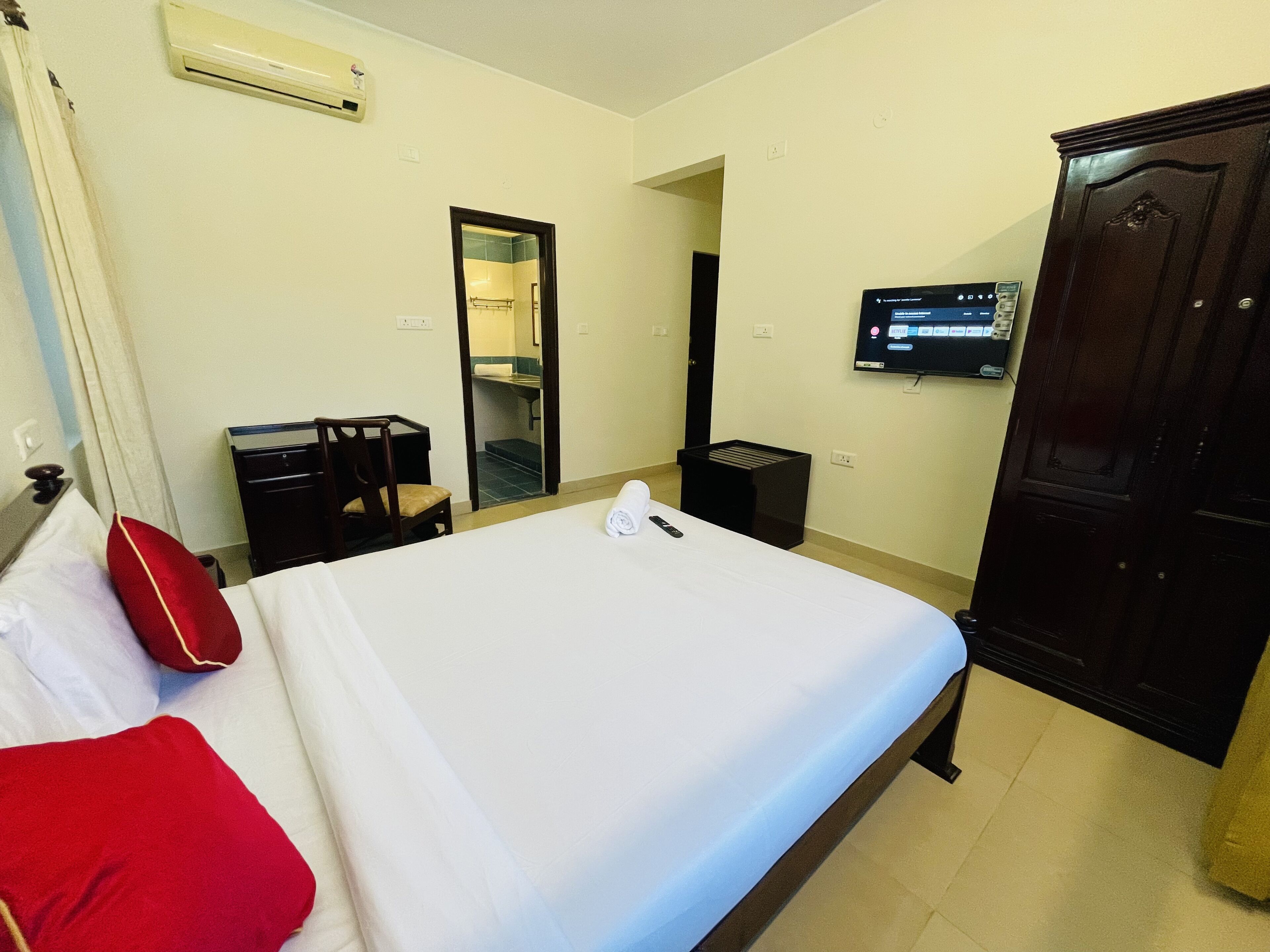 Une chambre d’hôtel équipée d’un lit, d’un bureau, d’une chaise, d’une armoire, d’un miroir et d’une télévision.
