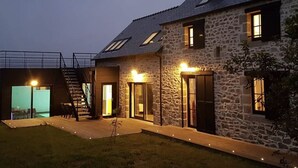 Een stenen huis met een trap naar een tweede verdieping, een overdekt terras en een zwembad.
