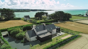 Een modern huis met een grote tuin, uitzicht op zee en omliggende velden.