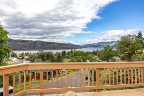 Enjoy a serene view of the surrounding landscape from this deck, overlooking a residential area and a large body of water.