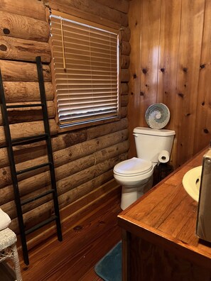 A wooden cabin bathroom with a toilet, sink, and ladder. -  Cabin By the Bay A unique authentic log cabin by the beach with fenced yard (Panacea)