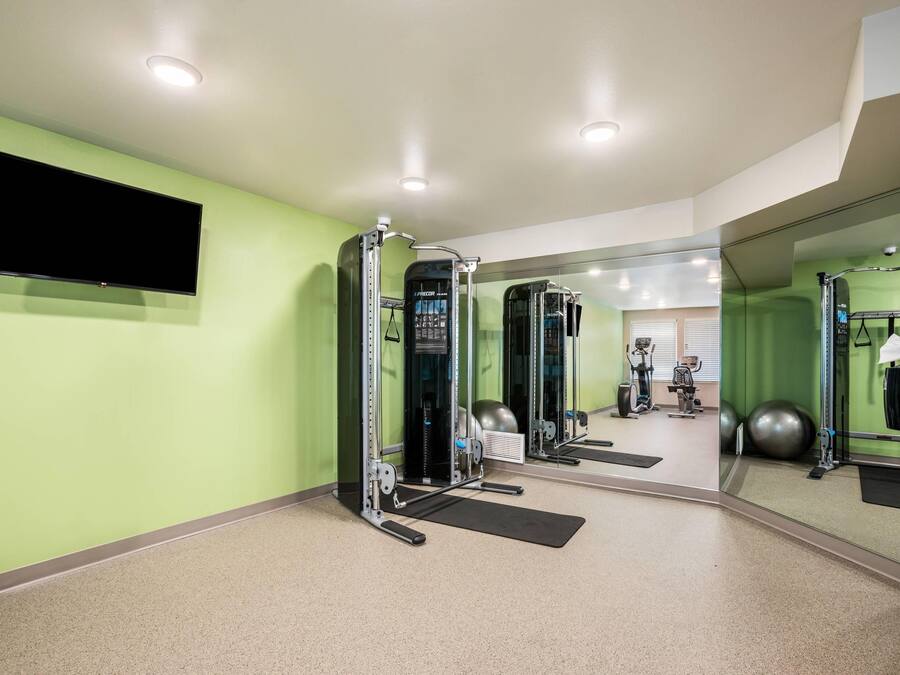 Een sportschool met trainingsapparatuur, een televisie en een spiegel.
