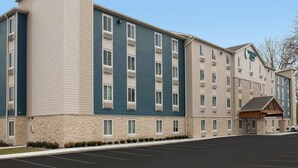 A multi-story hotel with a stone facade, multiple windows, and a parking lot. - Woodspring Suites Littleton-South Denver (Littleton)