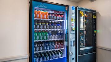 Máquina de vendas com frente azul identificada com 'AQUAFINA' e variedade de bebidas.