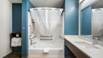 A modern bathroom with a bathtub, shower, and sink.