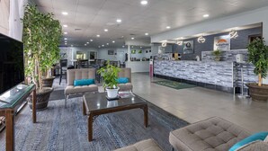 A spacious lobby with a reception desk, seating area, and a television. - Suburban Studios Rock Hill Northeast I-77 (Rock Hill)