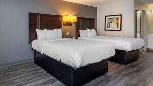 A double bed with a headboard, a bedside table, and a wall-mounted lamp. - Suburban Studios Rock Hill Northeast I-77 (Rock Hill)