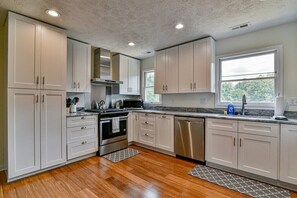 A kitchen with white cabinets, stainless steel appliances, and a window providing natural light.