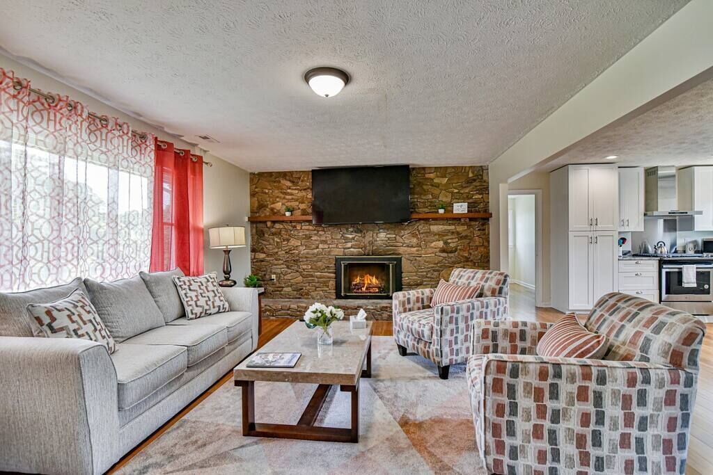A living room with a stone fireplace, a sofa, a coffee table, and a television.