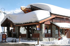A snow-covered building with a sign indicating it's a ski rental location.
