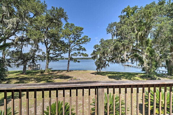 Enjoy serene lakeside views from this tranquil deck, surrounded by lush greenery and mature trees.