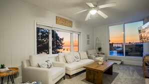 Sala de estar com uma grande janela, um ventilador de teto e uma placa com a inscrição 'Beach House'.