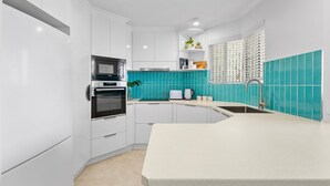 Una cocina moderna con armarios blancos, horno empotrado, microondas y lavaplatos.