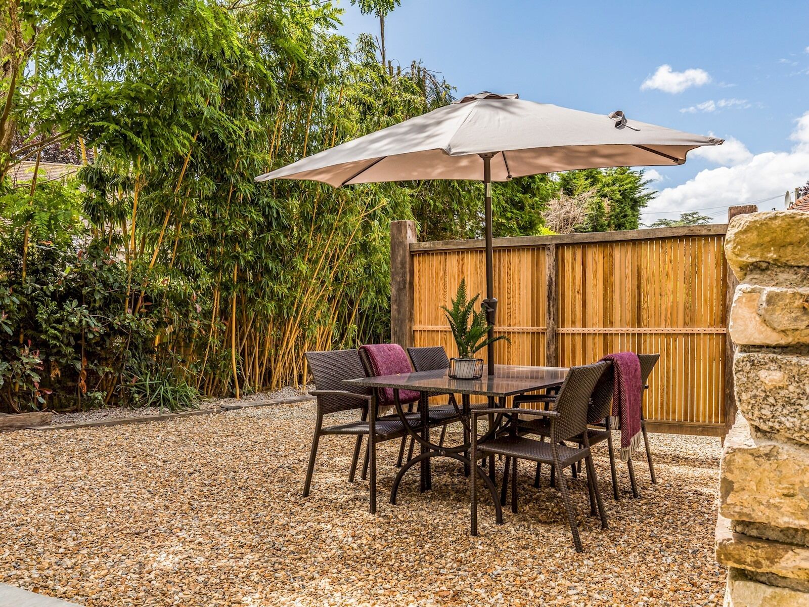 A patio with a table and chairs, an umbrella, and a wooden fence.