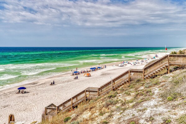 A beach with a wooden boardwalk, sandy beach, and ocean view.