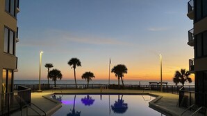 Uima-allas, josta avautuu näkymä merelle auringonlaskun aikaan. Allasta ympäröivät palmut ja aita.