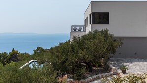 Un edificio moderno con piscina, immerso nel verde e con vista su un corpo d'acqua.