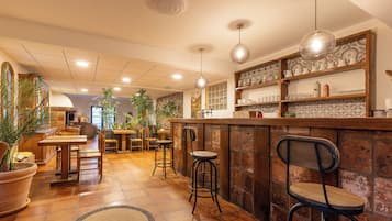 Een gezellig restaurant met een rustieke bar, houten tafels en stoelen, omgeven door potplanten en een betegelde vloer.