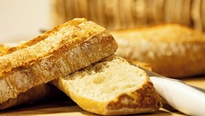Slices of toasted bread on a wooden cutting board with a knife.