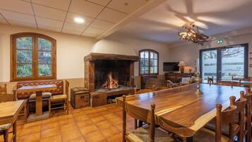 A cozy room with a fireplace, wooden furniture, and large windows.