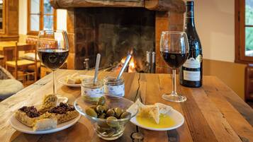 Et træbord med en vinflaske, glas, oliven, brød og en skål med oliven.