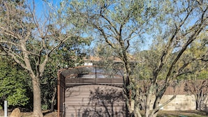 A rustic wooden structure with a sloped roof, surrounded by trees and a clear sky.