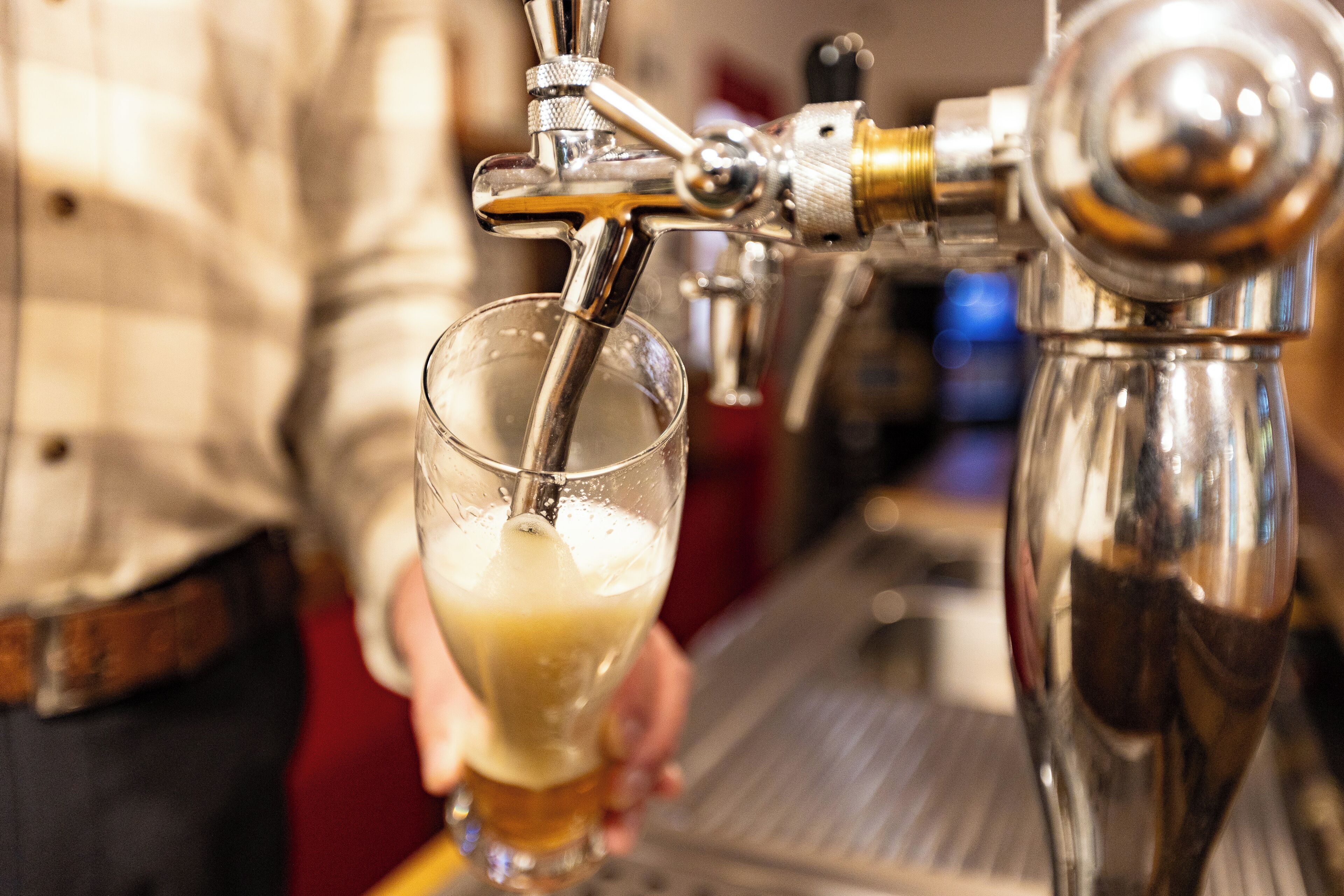 A tap dispensing beer into a glass held by a person.