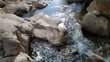 A river flowing through a rocky landscape with large boulders and trees with yellow leaves.
