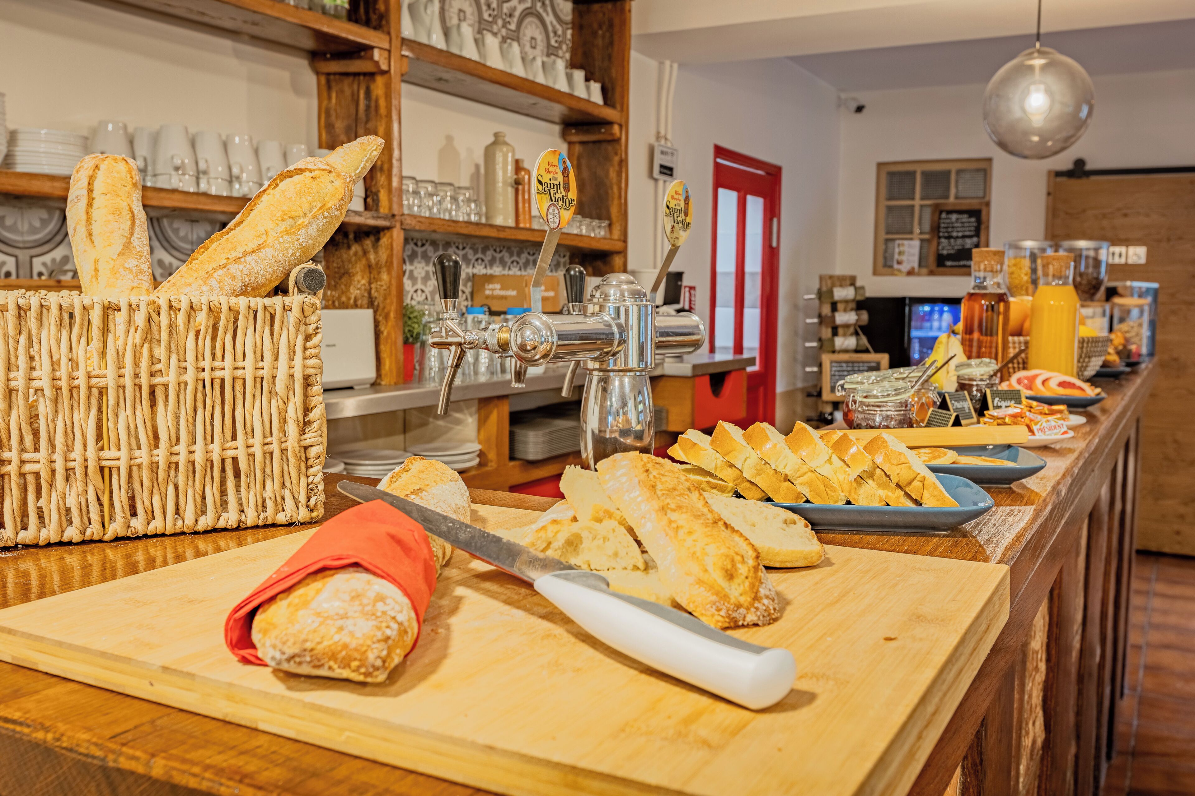 Mostrador de panadería con panes y pasteles diversos, una tabla de cortar y un cuchillo.