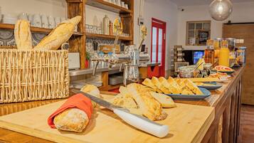 Mostrador de panadería con panes y pasteles diversos, una tabla de cortar y un cuchillo.