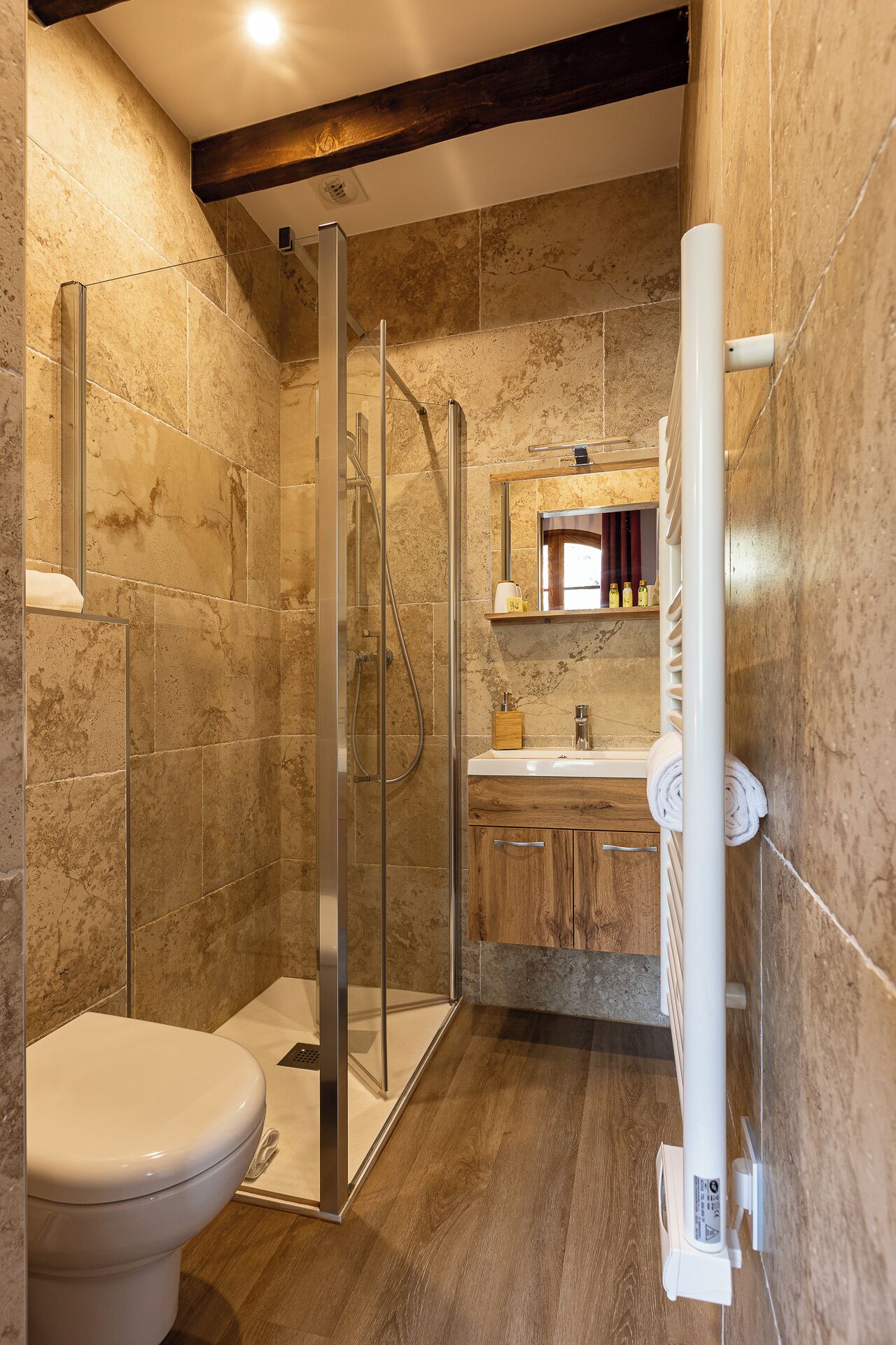 A modern bathroom with a glass-enclosed shower, a wooden vanity, and a toilet.