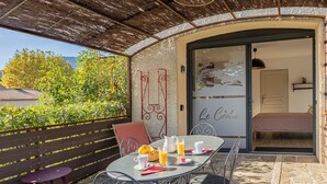 An outdoor dining area with a table set for breakfast, a wicker basket, and a glass pitcher.