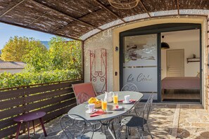 An outdoor dining area with a table set for breakfast, a wicker basket, and a glass pitcher.