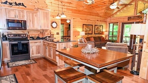 A wooden cabin interior with a kitchen, dining area, and seating space.