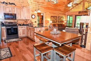 A wooden cabin interior with a kitchen, dining area, and seating space.
