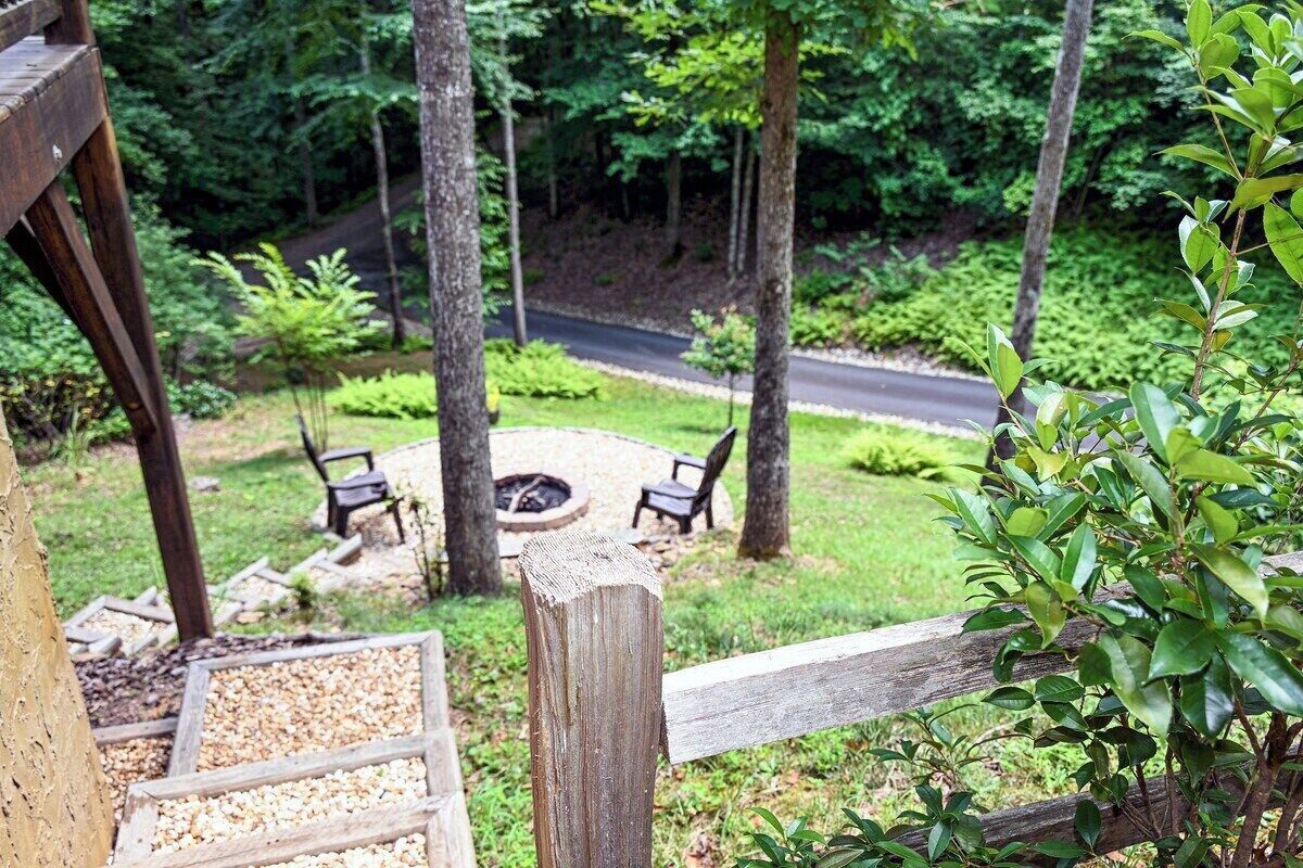 A wooden deck with a gravel area, surrounded by greenery and a fire pit.