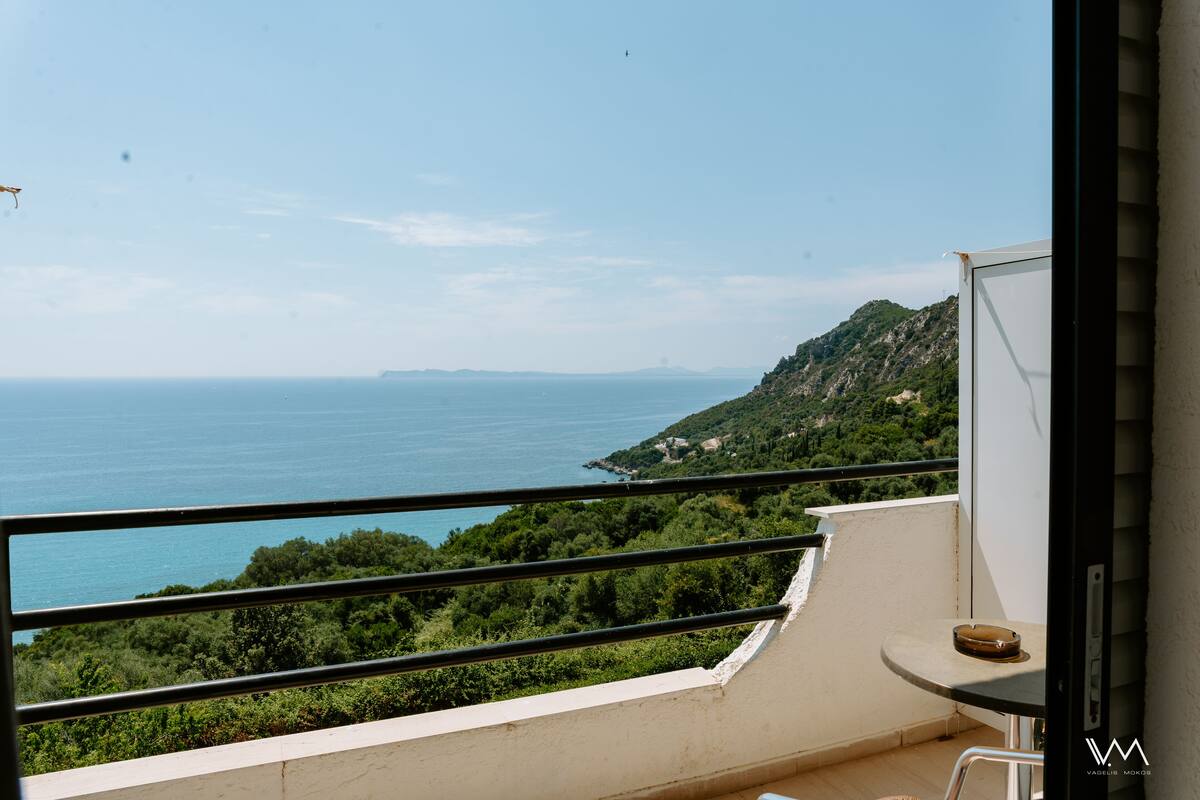 A balcony with a view of the sea and greenery.