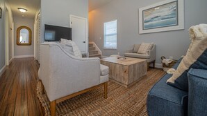 Ein modernes Wohnzimmer mit grauem Sofa, einem Holztisch und einem Fernseher.