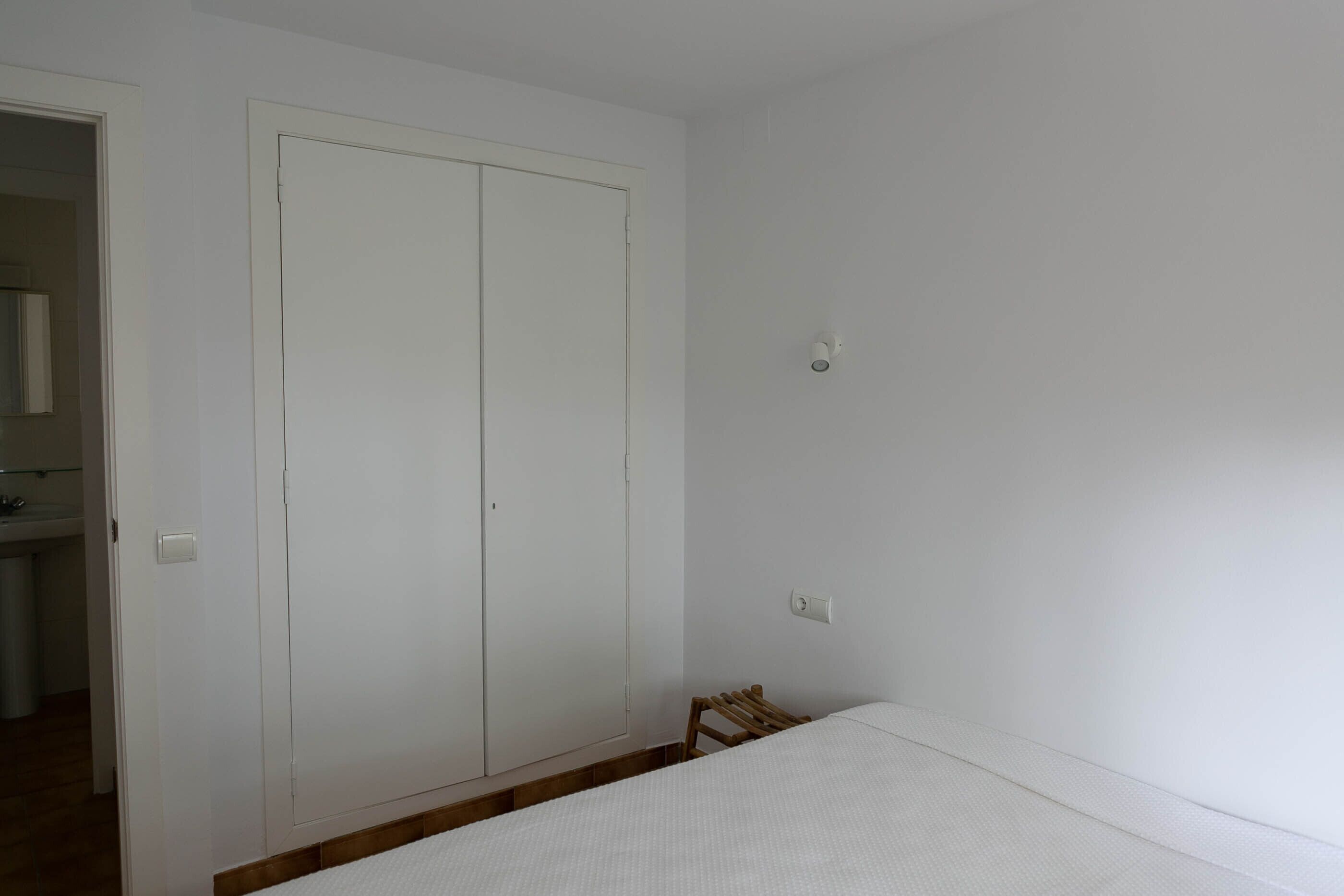 Une pièce comprenant un lit, une armoire et une petite chaise en bois.