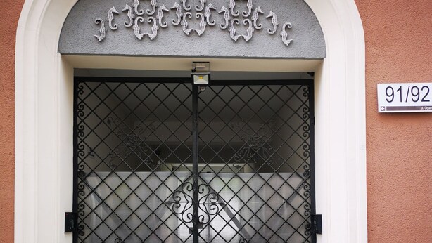 A double door with intricate metalwork and a number plaque above it. - Apartament Ogarna II (Gdansk)